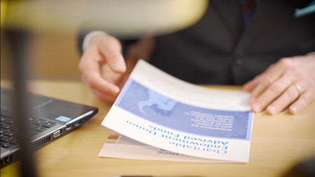 worker-looking-at-brochure-next-to-laptop