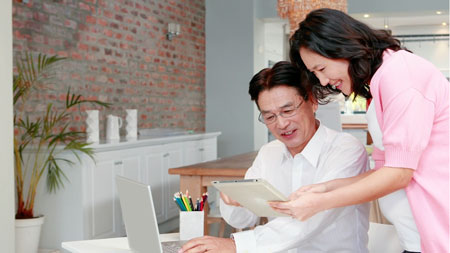 older-asian-couple-looking-at-tablet-smiling